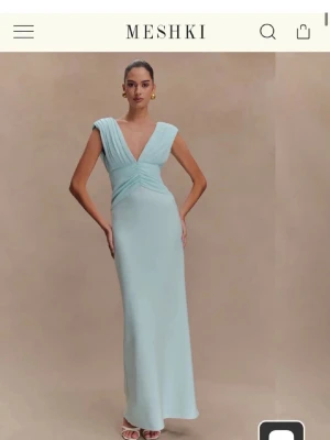 Ljusblå långklänning från Meshki - Elegant ljusblå långklänning från Meshki med djup v-ringning och breda axelband. Klänningen har draperad detalj över bysten och en figurnära passform. Helt ny med prislapp kvar! 