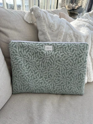 Grön datorväska med bladmönster från Emelo - Stilren datorväska från Emelo i ljusgrönt tyg med vitt bladliknande mönster. Väskan har en rektangulär form och stängs med vit dragkedja. Insidan är vit och vadderad för extra skydd. Perfekt för dig som vill ha en snygg och unik laptopväska. Passar laptop med maxmått: 33x24cm