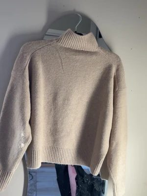 Beige stickad polotröja - Mysig beige stickad polotröja med avslappnad passform och ribbade muddar vid ärmslut och nederkant. Tröjan har hög krage och är tillverkad i ett mjukt material som passar perfekt för kyliga dagar. Från Zara och med prislapp kvar