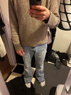 Beige stickad tröja hm - En stilren beige stickad tröja med rund hals och ribbade muddar vid ärmslut och nederkant. Tröjan har en klassisk passform och är perfekt för lager-på-lager under kyliga dagar. Materialet ser ut att vara ull eller ullmix. Hm