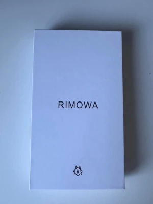 Rimowa silver mobilskal i aluminium - Snyggt och stilrent mobilskal från Rim i silverfärgat aluminium med räfflad design och logga längst ner. Skalets hårda material ger en exklusiv känsla och passar perfekt för dig som vill ha ett unikt och tåligt skydd till din mobil.