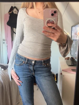 Ljusgrå långärmad topp - Säljer en ljusgrå topp med lång ärm och rundad halsringning. Toppen har en tight passform och är tillverkad i mjukt bomullsmaterial. Perfekt till jeans eller kjol för en enkel och snygg look.