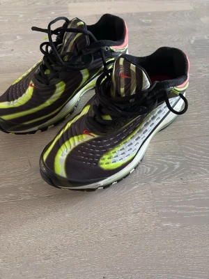 Nike Air Max sneakers  - Nike Air Max sneakers med svart och neongul ovandel, vita och grå detaljer samt röd häl. Synlig Air Max-sula med neongult inslag, svarta skosnören och meshmaterial för bra ventilation. Snygg sportig look med tydlig Nike-logga på sidan. Storlek 42.5 i väldigt fint skick efter bild. Kan gå ner i pris vid snabb och smidig, bara höra av sig!!!