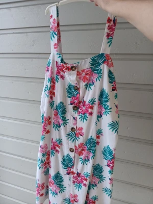 Två somriga klänningar  - Säljer två klänningar: en vit med rosa och gröna blommor, knappar framtill och breda axelband, samt en blå klänning med vita småblommor och puffärmar. 🌴🌺 Perfekta för varma dagar och båda har en lätt och luftig känsla. Skulle säga att båda passar flickor i 9-11 års åldern. Båda för 130 eller en för 80 kr! 🫧💰