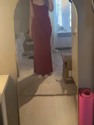 Röd långklänning- Tiger mist - Säljer en röd långklänning från ASOS. Figurnära passform. Klänningen har en enkel och elegant design med djup urringning i ryggen . Perfekt för bal eller fest.