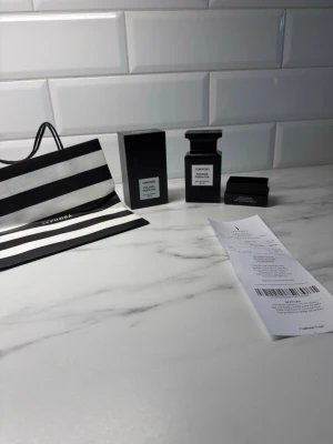 Tom Ford parfym Noir de Noir - Lyxig parfym från Tom Ford, Noir de Noir, i en elegant svart flaska med matchande svart kartong. Flaskan har en stilren, fyrkantig form och tydlig etikett framtill. Kommer med originalförpackning och Sephora-påse.