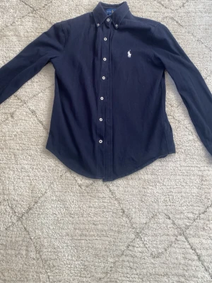 Mörkblå skjorta från Ralph Lauren - Polo Ralph Lauren skjorta mörkblå, storlek XS, använd ett fåtal gånger, hör av er vid minsta fundering!😀