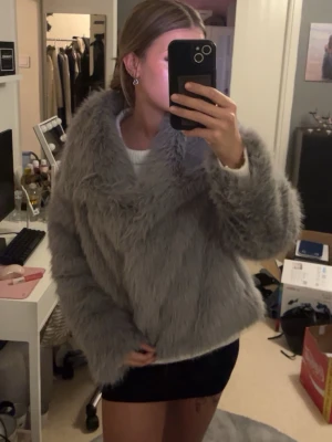 Grå fluffig fuskpälsjacka - Säljer en supermjuk och fluffig grå fuskpälsjacka med bred krage och lång ärm. Jackan har en oversized look och är perfekt för kalla dagar. Passar dig som vill ha en trendig och mysig vinterjacka med extra attityd. Aldrig använd utan bara testad