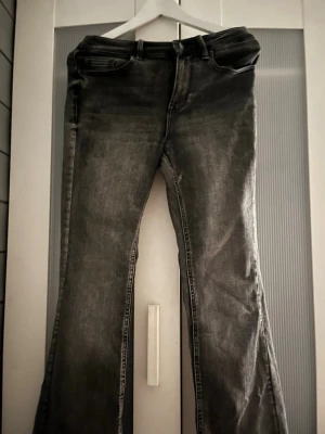 Grå bootcut jeans från Vero Moda - Säljer ett par grå bootcut jeans från Vero Moda. Jeansen har en snygg tvättad look och klassisk femficksmodell. Tillverkade i denim med lätt stretch för skön passform. Perfekta till sneakers eller boots.