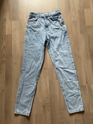Ljusblå jeans från gina tricot - Säljer ett par ljusblå jeans från gina tricot. Klassisk femficksmodell med hög midja och raka ben. Jeansen är i ett mjukt denimtyg och har en snygg vintagekänsla. Perfekta till sneakers eller boots!