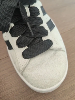 Mintgröna Adidas sneakers med svarta ränder - Fräscha mintgröna sneakers från Adidas med klassiska svarta ränder på sidorna och breda svarta skosnören. Ovandelen är i mocka och sulan är vit med en beige kant. Perfekta för en stilren och sportig look. Endast använda två-tre gånger.❤️