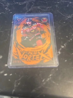 Hockeykort Polar Vortex Allard - Unikt hockeykort med spelaren Allard från Polar Vortex-serien. Kortet har en färgstark orange och svart design och ligger i ett genomskinligt plastfodral. Perfekt för samlare av sportkort och hockeymemorabilia. Numrerat till 20/65 ner lagd i en plast ficka som skyddar kortet 