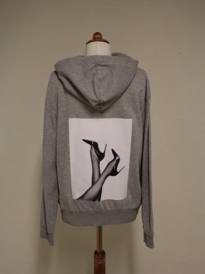 Grå hoodie med tryck från Reuse - Snygg grå huvtröja high heels, i storlek M lite kroppad och tunnare än vanliga huvtröjor, stilren och riktigt snygg🤩Liten i storleken 