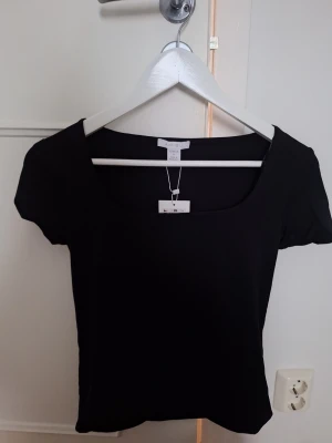 Svart topp med ringning - En helt ny svart topp från Newyorker. Toppen är tillverkad i mjukt bomullsmaterial som känns skönt mot huden. Perfekt att matcha med jeans eller kjol. 