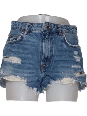 Blå denimshorts med slitningar - Snygga blå jeansshorts i klassisk denim med råa kanter och slitna detaljer framtill och baktill. Shortsen har fem fickor, knappgylf  . Perfekta för en avslappnad och trendig sommarstil.