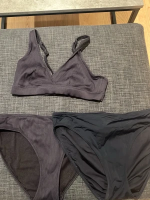 Svart bikini med ribbad topp - Säljer en svart bikini med ribbad topp och matchande ribbade trosor samt ett extra par släta svarta bikiniunderdelar. Toppen har breda axelband och en enkel, sportig design. Materialet är stretchigt och bekvämt, 