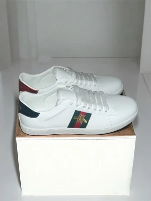 Gucci vita sneakers - Snygga vita sneakers från Gucci. Skorna är i läder och har vita snören. Perfekt för dig som vill sticka ut med exklusiv stil.