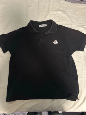 Moncler pike - Säljer nu denna riktigt snygga svarta Moncler pikén i storlek XL, den sitter dock mer som M enligt mig men fråga om mått på den om ni är osäkra på längd osv🙌tyvärr inte autentisk Moncler men ser ut som det!🍾⭐️