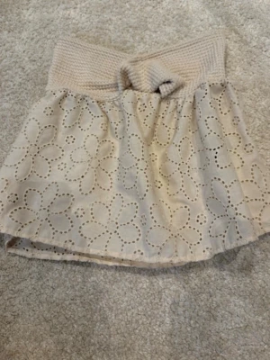 Beige kortkjol med spets och rosett - Supersöt beige tubtopp med bred ribbad kant upptill och en dekorativ rosett framtill. Perfekt för varma dagar. 