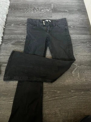 Svarta bootcut jeans Gina Tricot - Säljer ett par svarta bootcut jeans från Gina Tricot. Jeansen har klassisk femficksdesign, två knappar i midjan och är tillverkade i ett mjukt denimtyg. Perfekta för dig som gillar en tidlös och avslappnad look.