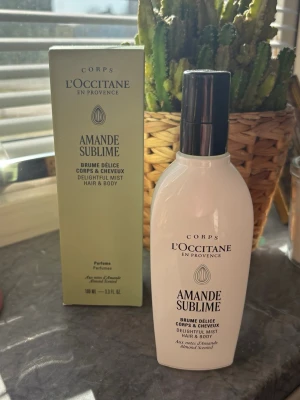L'Occitane Amande Sublime Mist - Fräsch kropp- och hårmist från L'Occitane, Amande Sublime. Flaskan är vit med svart spraykork och har elegant design. Doften har inslag av mandel och ger en lätt, lyxig känsla. Perfekt för dig som vill ha en subtil och fräsch parfymupplevelse. 100ml. Ny