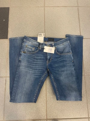 Blå tiger of Sweden jeans  - Snygga blå jeans från tiger of Sweden  med klassisk femficksdesign och raka ben. Jeansen har ljus tvätt med subtila slitningar framtill och kontrastsömmar. Perfekta för en avslappnad och trendig look.