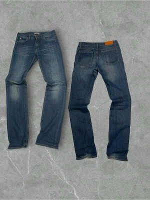  Acne Jeans (Hex Lena) - Säljer ett par klassiska blå jeans från Acne Jeans med rak passform och snyggt slitna detaljer. Jeansen har fem fickor, kopparfärgade nitar och en läderpatch bak i midjan. Tillverkade i slitstark denim med vintagekänsla.