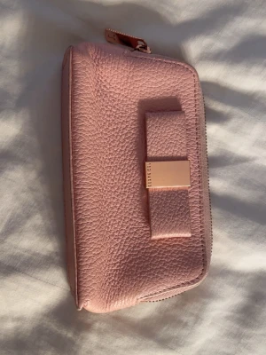 Ted Balker Rosa Plånbok -  Rosa plånbok med guldet, detaljer och rosett ifrån Ted Baker.