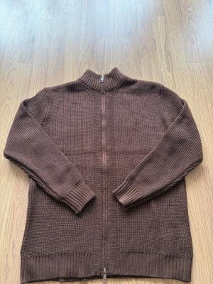 stickad ziptröja - Mysig brun stickad tröja med dragkedja hela vägen och hög ribbad krage. Tröjan har långa ärmar och ribbade muddar vid ärmslut och nederkant. Perfekt för lager på lager och chill höst- och vinterstil.