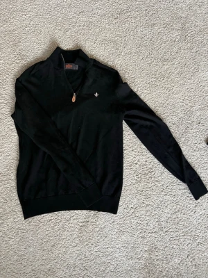 Svart Morris stickad tröja med halvzip - Aldrig använd utan bara testad på!!! Snygg svart stickad tröja från Morris med halvzip och liten silverfärgad logga på bröstet. Tröjan har ribbade muddar vid ärmslut och nederkant samt en klassisk krage. Perfekt till lager-på-lager och enkel att matcha. Stl S men passar även Xs