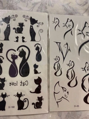 Svarta katt-tatueringar i ark - Två ark med temporära tatueringar i svart med olika kattmotiv. Motiven varierar från stiliserade siluetter till mer lekfulla och konstnärliga designer, vissa med texten 'Cat Love'. Perfekt för att piffa upp din stil med unika accessoarer.