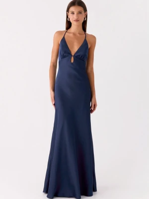 Sundowner Maxi Dress - Elegant marinblå långklänning med smala axelband och djup v-ringning från peppermayo. Klänningen har en liten cut-out framtill och är tillverkad i ett glansigt material som ger en lyxig känsla. 