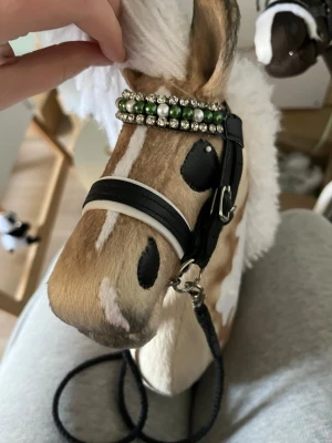 Käpphäst med vit man - Säljer en käpphäst med vit man, ljusbrun och vit päls. Hästen har broderade detaljer och tygöron. Perfekt för lekar och hobby horse-aktiviteter.