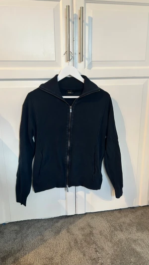 Svart ziptröja från Massimo Dutti - Snygg svart ziptröja från Massimo Dutti i extra fin bomull. Tröjan har hög krage, dragkedja framtill och ribbade muddar. Perfekt för en clean och stilren look. Skulle behövas strykas, annars i super bra skick. Tar bara plats. Ställ gärna frågor 😊