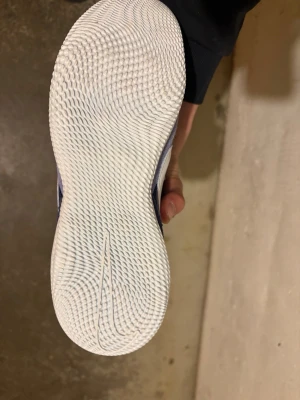 Nike blå fotbollsskor inomhus - Snygga blå Nike fotbollsskor för inomhusbruk med vit sula och vit swoosh på sidan. Ovandelen är i mocka och mesh för bra andningsförmåga och komfort. Skorna har klassisk snörning och röda detaljer på plösen.