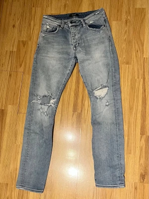 Neuw Jeans  - Säljer ett par grå jeans med slitningar och hål på båda benen. Jeansen har fem fickor, normal midja och raka ben. Perfekta för en avslappnad och trendig look. Materialet är klassisk denim med stretch med en slim passform (32:31). Vid minsta fråga är det bara skriva, mvh✌️
