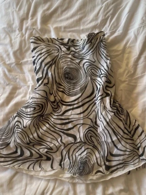 Vit och svart kjol med abstrakt mönster - Kjol med spiraler i vitt och svart från H&M, äldre kollektion. Väldigt unik och snygg! Slutar strax över knäna på mig som 165 cm. 