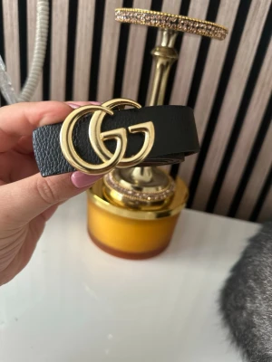 Svart  bälte med guldspänne -  Bältet är gjort i strukturerat skinn och har en stilren design som passar till det mesta. Perfekt accessoar för att lyfta din outfit.