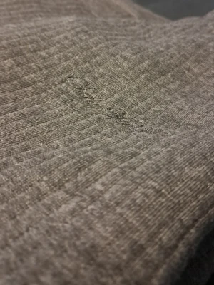 Grå stickad tröja med rund hals - Enkel och stilren grå stickad tröja med rund hals och långa ärmar. Tröjan har ribbade muddar vid ärmslut och nederkant för en bekväm passform. Perfekt att bära lager på lager och lätt att matcha med olika outfits. Materialet känns mjukt och stretchigt.