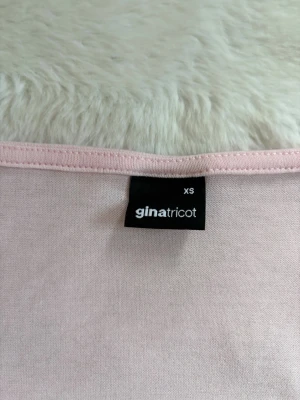 Ljusrosa omlottopp från Gina Tricot - Supersöt ljusrosa omlottopp från Gina Tricot i mjuk bomullsmix. Toppen har långa ärmar, v-ringning och knyt framtill för en trendig look. Perfekt att styla med jeans eller kjol för en fräsch outfit. Aldrig använt bara testat men säljer då den inte passar. Pris kan diskuteras 