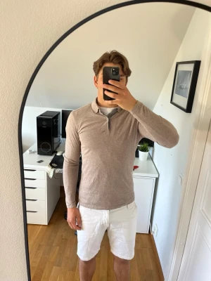 Beige långärmad pikétröja ifrån Massimo dutti - Säljer en beige långärmad pikétröja från Massimo dutti. Tröjan har en klassisk krage, knappslå utan synliga knappar och är tillverkad i mjuk bomull. Hör gärna av dig vid frågor!