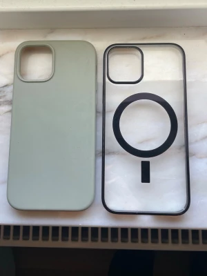 2 iPhone 12 skal - Säljer två mobilskal till iPhone 12. Ett är beige i  silikonmaterial, det andra är genomskinligt med svart ram. 