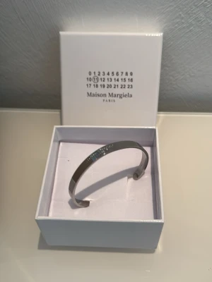 Maison Margiela silverfärgat armband - Snyggt och stilrent armband från Maison Margiela i silverfärgad metall. Armbandet har en minimalistisk design med märkets logotyp ingraverad på ovansidan. Perfekt accessoar för dig som gillar exklusiva detaljer och modern stil. Har 2 stycken så kom om du intresserad av att köpa 2