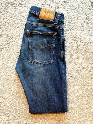 Nudie jeans - Säljer dessa otroligt snygga nudie jeans. Modell tight terry. Size W31 L30. Längd 97cm bredd 40cm. Jeansen är i perfekt skick och har en snygg färg nu till sommaren. Skriv vid fler frågor eller bilder!