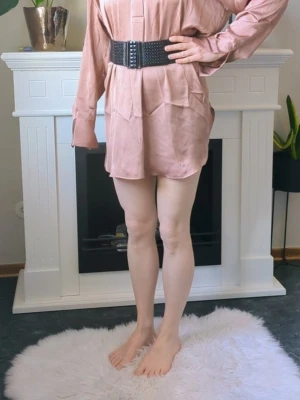 Glansig Oversize Skjortklänning H&M Storlek S-L - -Fin skjortklänning i oversizemodell. - Exakta färgen är svår att få på bild den är mörk krämig rosaaktig i färg ,det är svårt att beskriva färgen men den är jättefin. - Storlek S men då den är oversize så passar den M-L också . - Använd en gång på nyårs så i nyskick förutom att det är en skavank, ett märke på ena ärmen se de 2 sista bilderna.. - Jag kan ha missat någon miniskavank men jag har försökt att granska så gott det går.