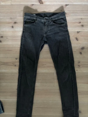 Mörkgrå jeans från J.Lindeberg - Snygga grå jeans från J.Lindeberg med klassisk femficksdesign och diskret logga vid fickan. Jeansen har en smal passform och är tillverkade i stretchigt denimtyg för extra komfort.