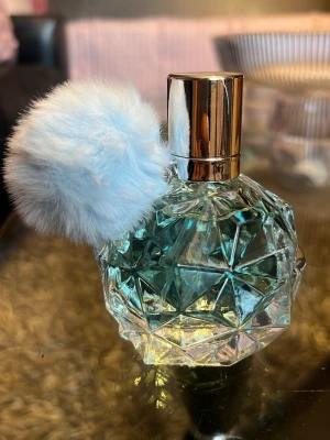 Helt ny parfym med blå tofs - Säljer en helt ny parfym i en cool, multifacetterad glasflaska med ljusblå vätska och en fluffig ljusblå tofs. Flaskan har ett guldigt lock som ger en lyxig känsla. Perfekt för dig som gillar snygga detaljer på parfymhyllan.