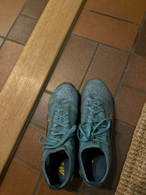 Blå Nike Mercurial fotbollsskor - Säljer ett par blå Nike Mercurial fotbollsskor skorna är i helt okej skick lite slitna dubbar men inga andra större defekter! Storleken är 44 och en väldigt snygg modell!!