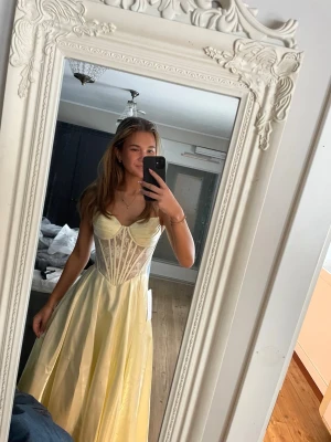 Ljusgul långklänning med snörning - Säljer min balklänning. Den är helt ny. Jag är 168cm och den passar mig bra i längden. Den har snörning i ryggen så passar många.