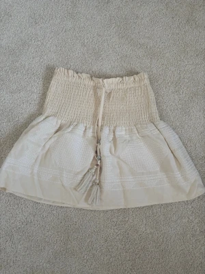 Kort kjol från Zara - En jättefin créme vit  minikjol med broderier på från Zara. Kjolen är endast använd ett par gånger och ser som ny ut.